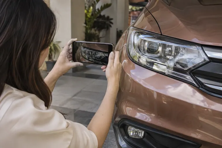 Pelanggan merakam lampu kereta yang diparkir dengan telefon